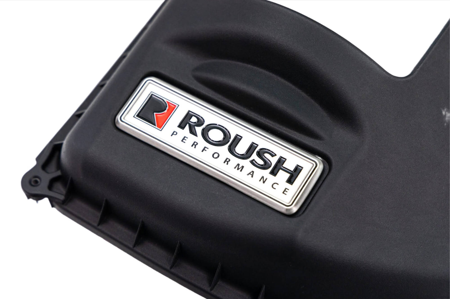 A black engine cover with the Roush Performance logo prominently displayed on a silver and red badge, designed as part of the Roush Bronco Air Induction System, perfect for enhancing your Ford Bronco's off-road racing experience.