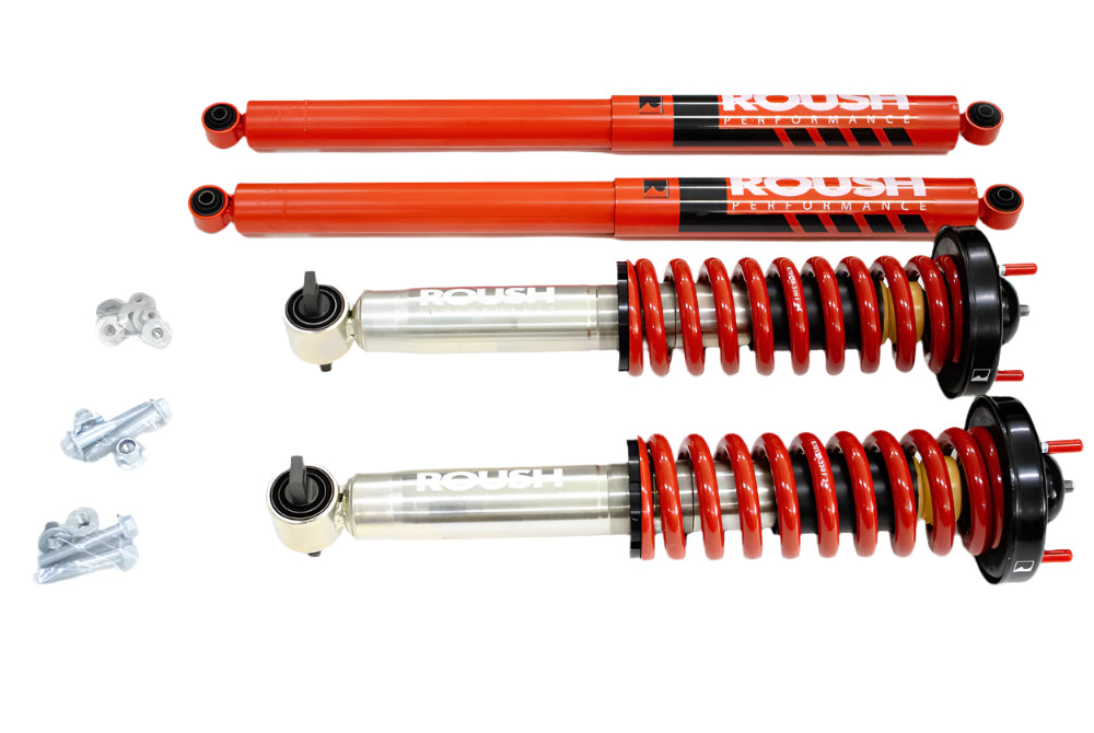 Red and silver automotive shock absorbers and coilovers with accompanying nuts and bolts, laid out on a white background, showcasing Roush Performance Suspension designed for F-150 Trucks' off-road capability.